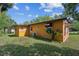 Side exterior view of the yellow home featuring the yard and shade awning at 612 Kensington St, Eustis, FL 32726
