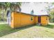 Exterior of yellow home featuring a door, window, small porch, and partial yard view at 612 Kensington St, Eustis, FL 32726