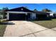 Charming single-story home featuring a black garage door, a well-maintained lawn, and an inviting front entrance at 6130 Gamble Dr, Orlando, FL 32808