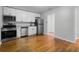 Modern kitchen with stainless steel appliances, white cabinets, hardwood flooring, and granite countertops at 819 State Ave, Daytona Beach, FL 32117