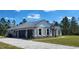 Side view of a house showing an attached two-car garage, stone accents, a metal roof, and a paved driveway at 947 Ferne Dr, Longwood, FL 32779