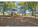 A community playground with climbing structures and slides provides a recreational area with mature trees in the background at 1233 Bramley Ln, Deland, FL 32720