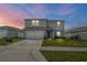 Charming two-story home features a two-car garage, manicured lawn, and a welcoming front entrance at dusk at 1506 Finnigan Cir, Haines City, FL 33844