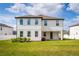 Exterior of the two-story home featuring lush green grass, beautiful landscaping, and a covered patio at 1639 Meadowlark Dr, Deltona, FL 32725