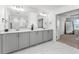 Bright bathroom with dual sinks, modern fixtures, gray vanity, and carrara tile flooring at 1639 Meadowlark Dr, Deltona, FL 32725