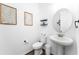 Stylish powder room with a pedestal sink, round mirror, and neutral decor, offering a clean and modern design at 1639 Meadowlark Dr, Deltona, FL 32725
