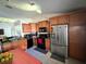 Well-lit kitchen featuring wood cabinets, stainless steel refrigerator and black appliances at 1931 Clarcona Rd, Apopka, FL 32703