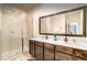 Bathroom featuring double vanity sinks, a large mirror, and a glass-enclosed shower at 2653 Roadster Ln, Kissimmee, FL 34746