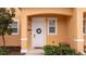 Close-up of the townhome front door with a wreath and well-manicured landscaping at 2653 Roadster Ln, Kissimmee, FL 34746