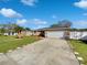 Charming single-story home with a well-manicured lawn, driveway, and a white garage door under a sunny sky at 2936 Woodcrest Ln, Lakeland, FL 33805