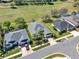 Aerial view of the neighborhood featuring well-maintained homes with mature trees and a pristine green field at 3624 Belle Rose Dr, Leesburg, FL 34748