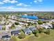 This aerial view showcases a beautiful neighborhood surrounding a serene lake with lush green spaces and clear blue skies at 3624 Belle Rose Dr, Leesburg, FL 34748