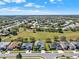 An aerial shot features a neighborhood with lush green spaces, well-kept homes, and tree-lined streets under a partly cloudy sky at 3624 Belle Rose Dr, Leesburg, FL 34748