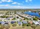 A scenic aerial view captures a residential area with a tranquil lake, lush greenery, and blue skies at 3624 Belle Rose Dr, Leesburg, FL 34748