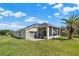 Expansive backyard featuring a well-maintained lawn, screened lanai, mature palm tree, and the property's rear exterior at 3624 Belle Rose Dr, Leesburg, FL 34748
