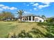Lush backyard showcasing a mature palm tree, a well-kept lawn and the exterior of the home at 3624 Belle Rose Dr, Leesburg, FL 34748