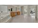 Bright bathroom featuring a soaking tub, glass block window, tile floor and vanity at 3624 Belle Rose Dr, Leesburg, FL 34748
