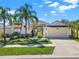 Inviting home exterior with a two-car garage, tropical landscaping, and a neatly kept lawn at 3624 Belle Rose Dr, Leesburg, FL 34748