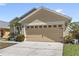 Beige single-Gathering home featuring a two-car garage, manicured landscape, and a cozy, welcoming ambiance at 459 Tivoli Cir, Davenport, FL 33837