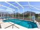 Inviting in-ground pool with a screened enclosure, poolside seating, and well-maintained landscaping at 459 Tivoli Cir, Davenport, FL 33837