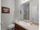 Well-lit bathroom featuring a single sink vanity, framed mirror, toilet, and glass-enclosed shower, with neutral-toned walls and tile flooring at 4631 Cypress Forest Ln, St Cloud, FL 34772