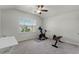 Spacious bedroom with neutral carpet, ceiling fan, and large window providing natural light, featuring exercise equipment at 4631 Cypress Forest Ln, St Cloud, FL 34772