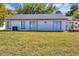 The back of a white home features sliding glass doors leading to a grassy lawn at 5307 Sandy Hill Dr, Orlando, FL 32821