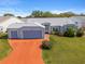 Attractive single-story home with a three-car garage, well-kept lawn, and a brick-red driveway at 5414 Zinnia St, Leesburg, FL 34748