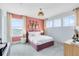 Charming bedroom featuring a pink accent wall, plush carpet, and bright natural light from multiple windows at 6033 Tree Crossing Ln, St Cloud, FL 34771