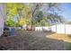 Grassy backyard featuring mature trees, flowering bushes, white fence, and a storage shed at 613 Andrew St, Altamonte Springs, FL 32714