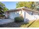 View of a single-story house with attached garage, brick accents, and a mature bush at 613 Andrew St, Altamonte Springs, FL 32714
