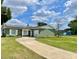 Charming, green single-story home featuring a welcoming front lawn, a driveway, and solar panels on the roof at 714 West Ct, Longwood, FL 32750