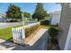 A sidewalk and manicured yard of the property featuring mature trees, shrubs, and a decorative picket fence at 8201 Se 169Th Palownia Loop, The Villages, FL 32162