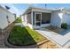 View of the home's back exterior featuring a screened-in porch, well-kept lawn, and decorative stone border at 8233 Se 169Th Palownia Loop, The Villages, FL 32162