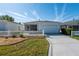 Inviting single-story home featuring a manicured lawn, white picket fence, and an attached two-car garage at 8233 Se 169Th Palownia Loop, The Villages, FL 32162
