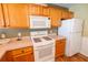 Close-up of the kitchen featuring wooden cabinets, white appliances, and ample counter space at 8233 Se 169Th Palownia Loop, The Villages, FL 32162