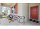 Inviting front porch featuring decorative stone accents, a cozy seating area, and a vibrant red front door at 917 Pearlwood Loop, Eagle Lake, FL 33839
