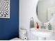 Stylish half-bathroom featuring modern sink, navy walls, and decorative art at 9513 Amber Chestnut Way, Winter Garden, FL 34787