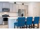 Close up of kitchen showcasing the stainless steel appliances, quartz countertops, tile backsplash, and three blue bar stools at 9513 Amber Chestnut Way, Winter Garden, FL 34787
