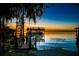 Sunset view of private dock with boat lift on tranquil lake surrounded by trees with hanging moss at 5243 W Lake Butler Rd, Windermere, FL 34786