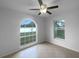 A bedroom with a ceiling fan, tile floors, and natural light from the arched and regular windows at 546 Koala Dr, Kissimmee, FL 34759