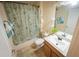 Cozy bathroom with seashell shower curtain, and warm wood vanity at 7732 Sloewood Dr, Leesburg, FL 34748