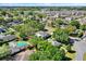 Aerial view of a neighborhood showcasing many houses with mature trees and a pond in the background at 9649 Water Fern Cir, Clermont, FL 34711