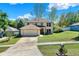 Two-story home featuring manicured front yard and driveway leading to a two-car attached garage under a bright sky at 9649 Water Fern Cir, Clermont, FL 34711