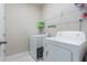 A laundry room features a washer, dryer, and shelving for storage of cleaning supplies at 15221 Sunrise Grove Ct, Winter Garden, FL 34787