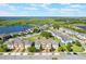 Aerial view of townhomes with surrounding greenery and a scenic lake in the background under a blue, partly cloudy sky at 15221 Sunrise Grove Ct, Winter Garden, FL 34787