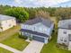 Aerial view of a two-story blue home featuring a lush lawn, a dark roof, and a long driveway at 16805 Sunrise Vista Dr, Clermont, FL 34714