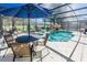 Outdoor dining and relaxing area with view of a screened-in pool and rock waterfall at 16805 Sunrise Vista Dr, Clermont, FL 34714