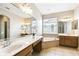 Bathroom featuring dual vanities, a soaking tub, neutral tile, and a large mirror at 2480 Northumbria Dr, Sanford, FL 32771