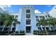 Modern condo exterior featuring multiple stories and private balconies, complemented by lush tropical landscaping at 4741 Clock Tower Dr # 201, Kissimmee, FL 34746